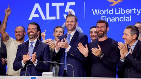 Trump and sons' stake in crypto firm worth $5bn Bloomberg/Getty Eric and Donald Trump in dark blue suits and light blue ties clap hands at the Nasdaq stock exchange surrounded by other executives from World Liberty Financial in August 2025