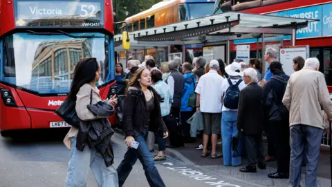 London Tube strike enters third day with more disruption reported EPA/Shutterstock A large group of people queue at a busy London bus stop next to red double-decker buses, with two women walking past in the foreground.