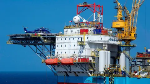 Net-zero 'not a platitude' for oil and gas sector Getty Images A helicopter sits idle on a helipad attached to the Culzean oil production platform in the North Sea