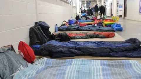 Peterborough rough sleeper centre to offer women-only sessions Light Project Peterborough Sleeping bags laid out on the floor of a concourse in the stadium. People are gathered in the distance.