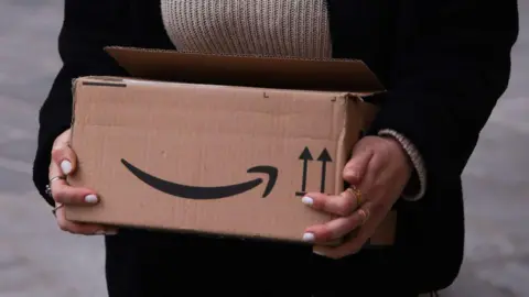 Nurphoto via Getty A person carries an Amazon cardboard box in Bologna Italy in March 2025
