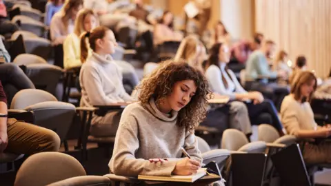 University students like me are happier living at home Getty Images A group of students in a lecture theatre, sat down making notes