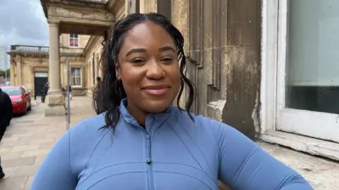 Scotland scrapped peak rail fares A smiling Kara Smith outside of a train station