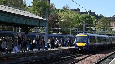 Peak time rail fares srapped on ScotRail trains Getty Images A ScotRail train arrives at Waverly station in Edinburgh in the sunshine, the castle in the background. People are making their way off the train and up the platform.