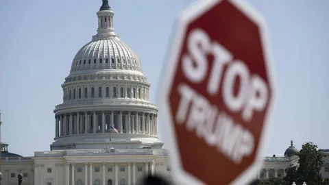 Anadolu via Getty Images File image of the US Capitol building with a blurry sign in the foreground that reads "stop Trump"