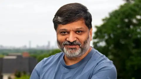 The Caribbean island making millions from the AI boom HubSpot A picture of Dharmesh Shah stood at a slight angle smiling at the camera. He's Indian, in his 50's and wearing a blue t-shirt with black hair and a grey beard.