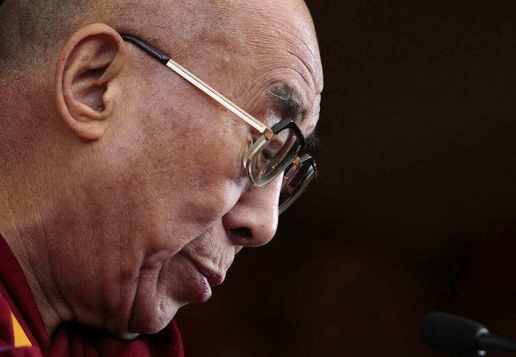 A man with glasses looks down.