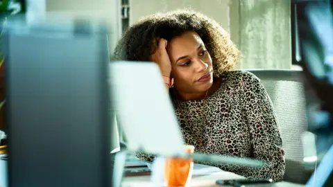 The two words you need to help you push back at work Getty Images A woman looking distant and stressed at her desk in the office