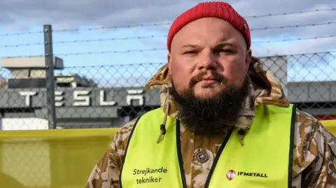 The striking Swedish workers taking on carmaker Tesla Striking Tesla mechanic Janis Kuzma standing on the picket line outside a Tesla garage in Malmö