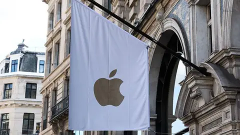 UK court loss could cost Apple £1.5bn Getty Images A white flag bearing a gold apple logo hangs outside the stone front of an apple store