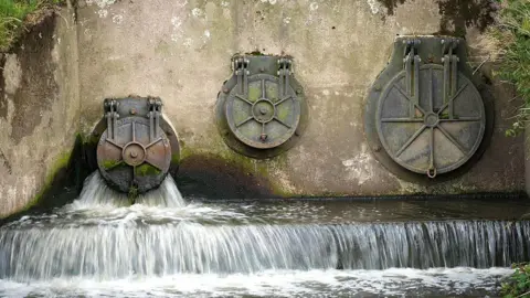 Water companies told to refund £260m to customers. Getty Images Water discharges from an outlet pipe. There are three pipes shown on a concrete wall with some moss visible.