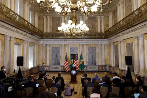 Bankers on edge, a gilded cash room and US blaming China Getty Images A large gilded room with then Treasury Secretary Janet Yellen addressing an audience. There are neo-classical pillars lining the walls and marble inlays and a gold mezzanine balcony halfway up the cavernous walls.