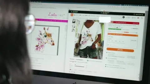 Temu agrees to remove rip-off greeting cards more quickly BBC/Lola Design An over the shoulder photograph of greetings card designer Amanda Mountain looking at a computer screen where she is comparing her giraffe painting to a Temu t shirt with her design on it