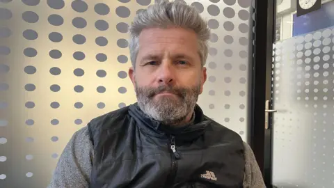 The new hubs saving Yorkshire towns from becoming banking deserts Kit Taylor/BBC A man with silver hair and a black body warmer, in front of a window.