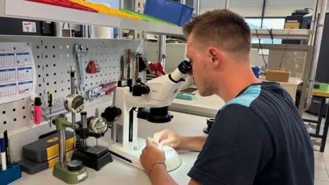 Swiss companies target alternative export markets MPS An MPS worker with short hair looks into a microscope