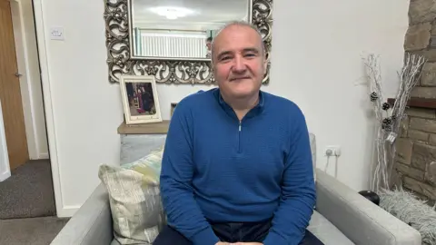 Horizon sub-postmasters call for retrial in Post Office murder case A middle-aged man on a sofa looking at the camera