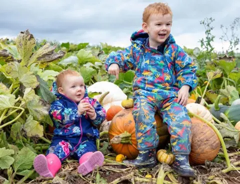 Spooky spending creeping in weeks before Halloween BBC/Andy Owens Two young children sit in a pumpkin patch. It's a cloudy overcast day and they are dressed in colourful rainsuits and wellies