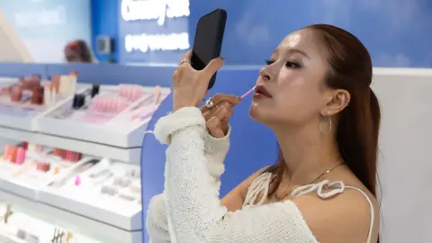 Should K-beauty products have to come from South Korea? PureSeoul A woman putting on make-up at K-beauty store PureSeoul in central London