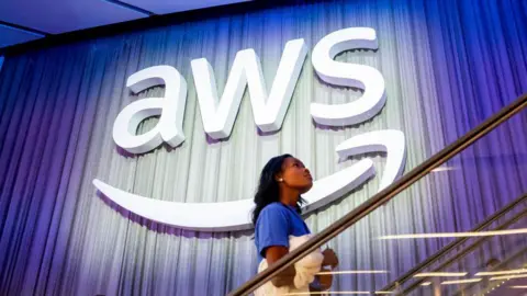 Amazon services 'recovering' as Snapchat and banks among sites hit by outage Getty Images A woman walking up stairs in front of a giant AWS sign. It is the three letters AWS with an Amazon smiley-face-like arrow underneath.