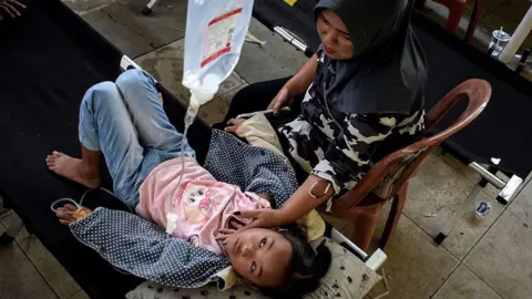 Indonesia food poisonings and protests test Probowo's first year in office Getty Images Salwa Nur Azmi, an elementary school student gets treatment in a makeshift clinic whilst she is suffering from food poisoning, after eating at the government's free meal programme