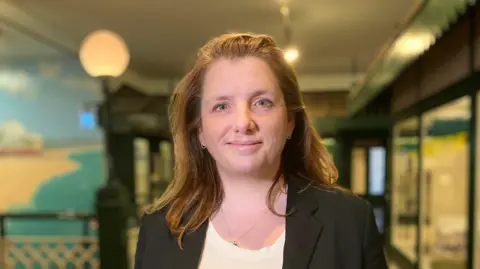 Matthew Richards/BBC A head and shoulders image of MP Alison McGovern. She is wearing a black blazer over a white top. She is smiling and looking into the camera.