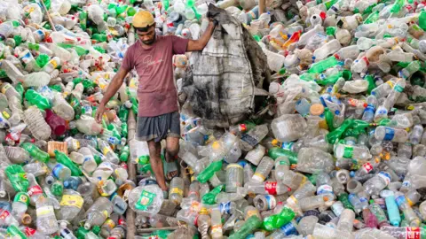 Can the plastic recycling industry be saved? Getty Images A man walks down a massive pile of plastic bottles in Bangladesh