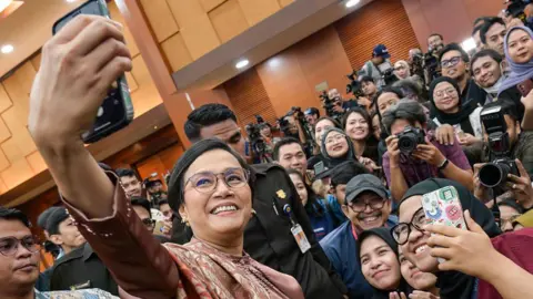 Indonesia food poisonings and protests test Probowo's first year in office Getty Images Former Indonesian Finance Minister Sri Mulyani Indrawati takes a selfie with journalists after the handover ceremony to her successor Purbaya Yudhi Sadewa