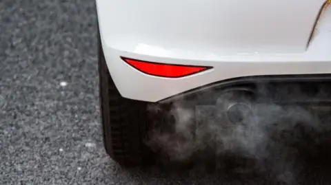 Getty Images A close up of a white car's exhaust pipe emitting fumes