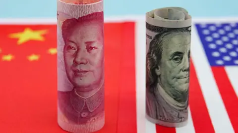Bankers on edge, a gilded cash room and US blaming China Getty Images Banknotes from China and US are rolled up and standing upright on flags of both countries