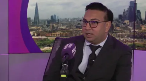 'You're willing to lose money, but not the person' BBC A man sitting at a microphone in the BBC London studio. He is wearing a suit and glasses, with a screen displaying the London skyline behind him.