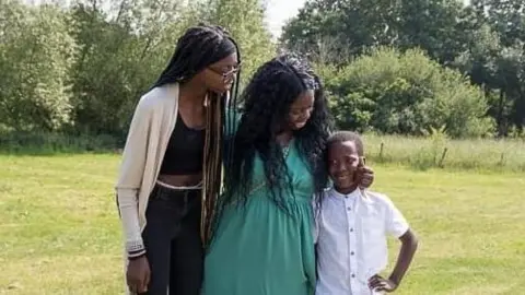 Haddy Folivi Haddy Folivi, flanked by her two children