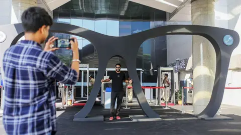 Bloomberg via Getty Images An attendee poses for photos with a giant pair of glasses following the Lenskart listing ceremony at the National Stock Exchange (NSE) in Mumbai, India, on Monday, 10 November 2025. 