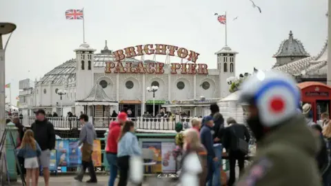 Getty Images Crowds of people in foreground with the pavilion on Brighton Palace Pier behind them.