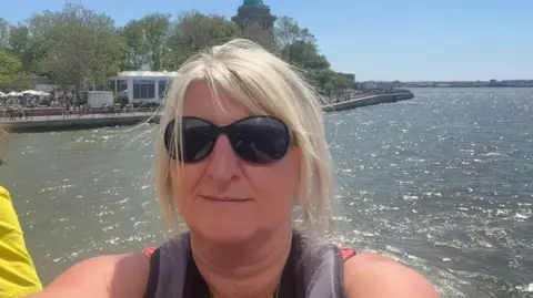 Eve Craven Eve Craven wearing sunglasses looking into the camera with sun shining on the water in the background