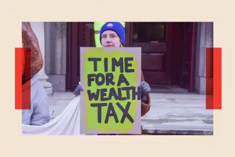 SOPA Images/LightRocket via Getty Images An activist holds a 'Time for a wealth tax' placard 