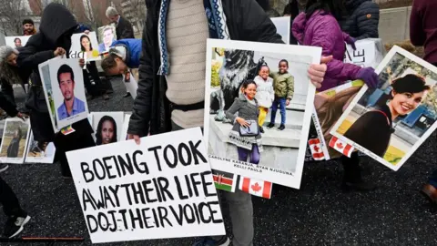 AFP via Getty Images Families and friends who lost loved ones in the March 10, 2019, Boeing 737 Max crash in Ethiopia, hold a memorial protestwitha  sign saying Boeing took away their life, DOJ their voice in front of the Boeing headquarters in Arlington, Virginia, on March 10, 2023 to mark the four-year anniversary of the event