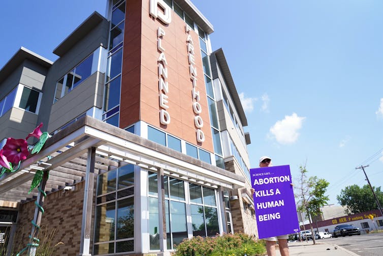 A woman holds a sign that says, 'Science says...abortion kills a human being.'