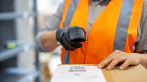 Getty Images Close-up of an anonymous female warehouse worker scanning package with bar code scanner