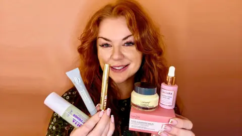 Rachael Parnell A ginger woman is holding up her favourite skin care to the camera. In one hand she has three tube like products and in the other she has another three products, one if in a box another in a tub and a third in a bottle