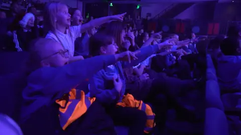 Pantomime is the bedrock of regional theatre, says Arts Council Children from Fieldhead Primary Academy in Kirklees are screaming and shouting and all pointing at the stage in a theatre.