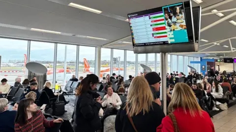BBC passengers looking at a screen in Edinburgh Airport