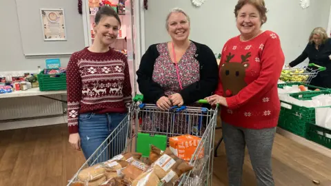 BBC Three volunteers from Cheylesmore Food Hub are standing behind a large shopping trolley full of bread
