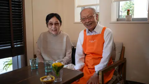 Japan is facing a dementia crisis – can technology help? Toshio Morita and his wife sitting at the Restaurant for Mistaken Orders before the start of his shift