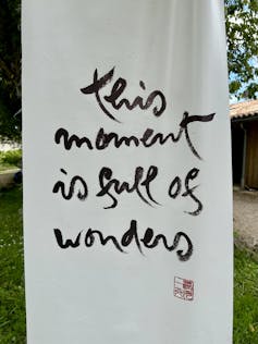 A white scroll with the words, 'This moment is full of wonders.'