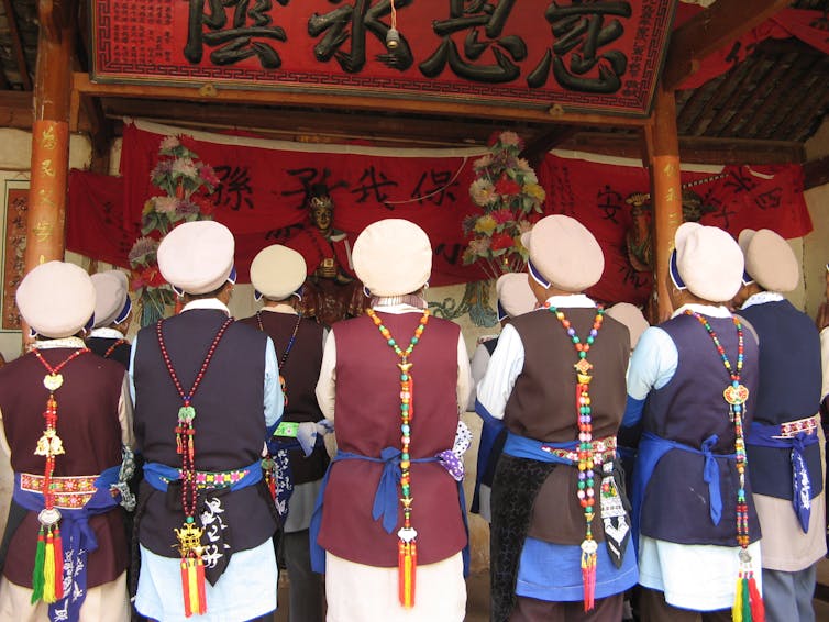 A group of women standing with their backs to the camera, facing a deity in a temple.