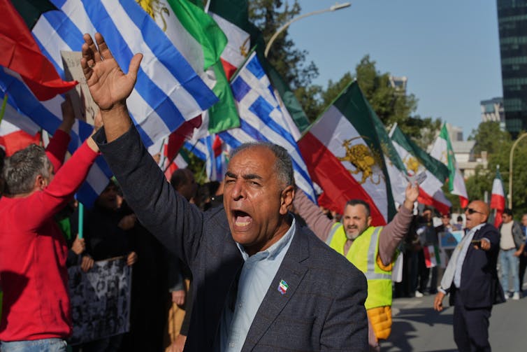 Demonstrators carry Iranian flags and chant slogans during a rally.