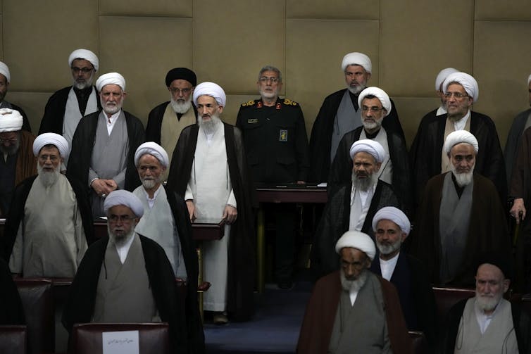 A group of men in Shia Muslim religious attire gather at a political forum.